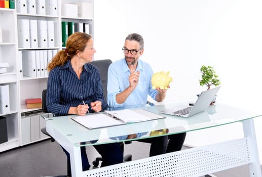 young businessman with piggy bank and businesswoman together in the office