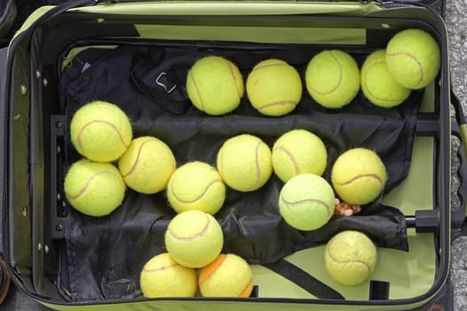 Several used green tennis balls in suitcase