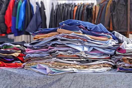Big piles of second hand clothing at flea market