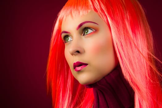 Beauty portrait of woman with colored wig and colorful makeup on purple background.