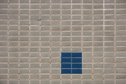 The modern façade of a building with angular clinker bricks with lattice holes.