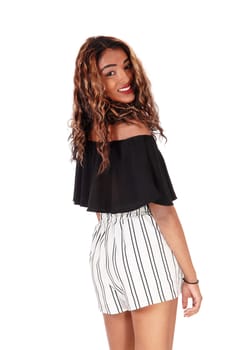 A gorgeous teen in a black blouse and white shorts standing from the.back looking over shoulder, isolated for white background.