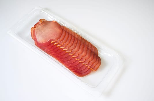 Some cut slices of iberian cured loin on the package. Isolated over white background