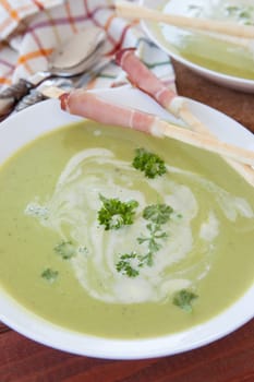 Homemade creamy pea soup and bread sticks with smoked ham