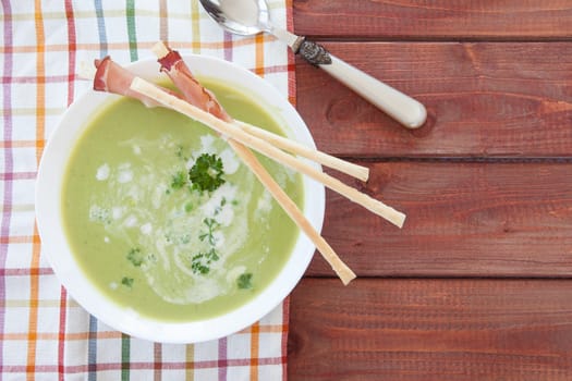 Homemade creamy pea soup and bread sticks with smoked ham