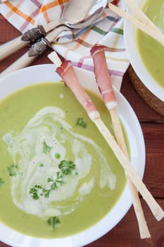 Homemade creamy pea soup and bread sticks with smoked ham