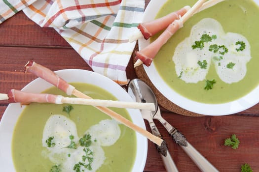 Homemade creamy pea soup and bread sticks with smoked ham