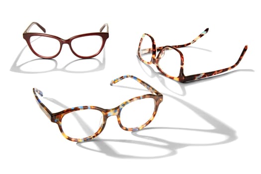 Studio photo of three pairs of glasses with long shadow isolated on white background.