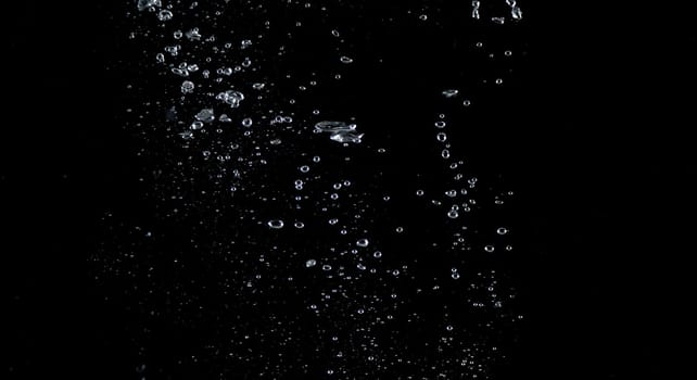 Close-up images of soda water splashing in the water to many little bubbles that make it feel like refreshing and black background