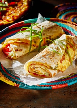 Two freshly made Ugandan Rolex Rolls served on a colorful woven indigenous basket made with egg omelette and vegetables rolled in a chapati