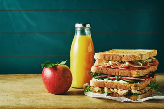 Lunch food set consist of sandwich, juice, apple on wooden table