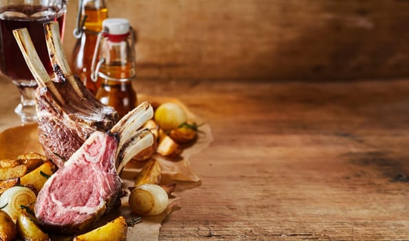 Serving of grilled lamb chops from a summer barbecue served with roasted vegetables on a rustic wood background with copy space