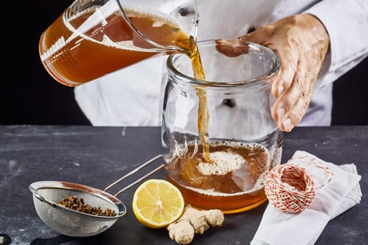 Man pouring kombucha SCOBY fermenting tea into jar