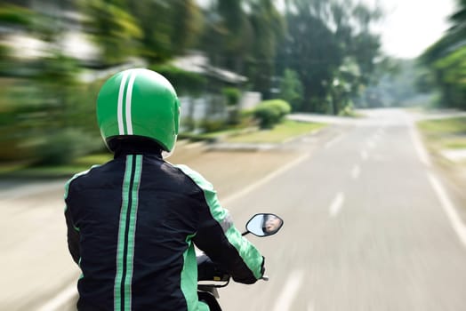 Rear view of motorcycle taxi driver rushing on the road