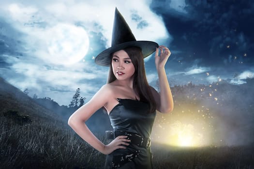 Beautiful asian witch woman with hat posing with full moon background