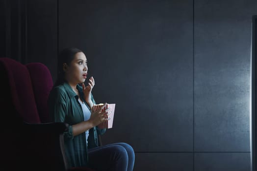 Portrait of asian woman with popcorn watching horror movie at home