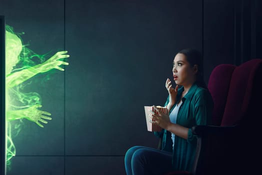 Shocked asian woman watching scary movie with popcorn at home
