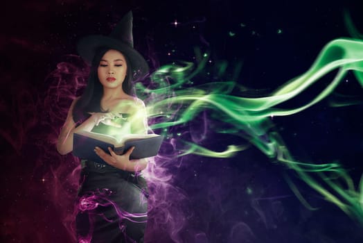 Pretty asian witch woman reading the incantation in book. Halloween concept