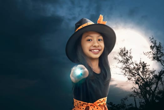 Happy asian witch girl with magic wand on the night