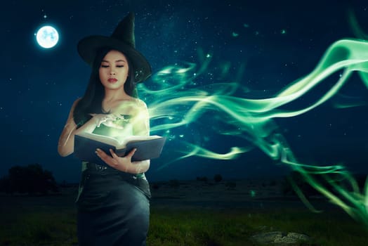 Beautiful asian witch woman learning the magic spell from book on the night