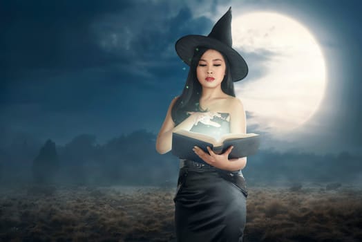 Young asian witch woman reading the spell books on the night