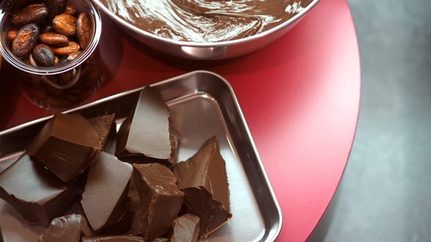 Close-up images of chocolate bar top view angle and cocoa seed with bowl of dark brown cream milk swirling by handmade for represent one of delicious sweet in the World