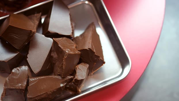 Close-up images of chocolate bar top view angle and cocoa seed with bowl of dark brown cream milk swirling by handmade for represent one of delicious sweet in the World