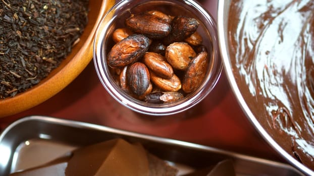 Close-up images of chocolate bar top view angle and cocoa seed with bowl of dark brown cream milk swirling by handmade for represent one of delicious sweet in the World