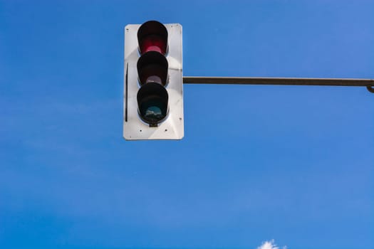 A traffic light and a surveillance camera on a pole mounted on the street.