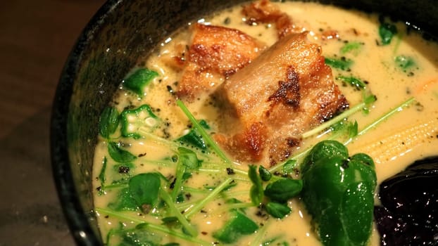 Close-up images of yellow color soup curry with chicken, pork and vegetable in bowl which famous traditional food menu and only found in Hokkaido Sapporo district of Japan