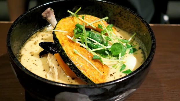 Close-up images of yellow color soup curry with chicken, pork and vegetable in bowl which famous traditional food menu and only found in Hokkaido Sapporo district of Japan