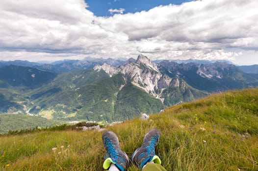 Hiker boots. Rambler having fun and enjoying wonderful breathtaking mountain view. Freedom concept. Italian Alps. Friuli Venezia Giulia. Concept of adventure.