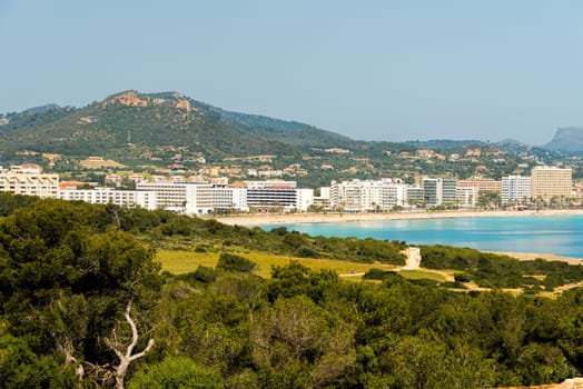 View to the beach of Cala Millor with the hotels and beach promenade with the hills and mountains in the background on the Spanish Mediterranean island Mallocra