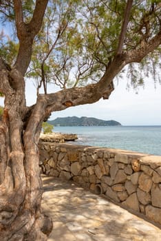 Natural stone wall on the promenade from the resort of Cala Millor with a view of the Mediterranean Sea and the hills on the Spanish Balearic island of Mallorca