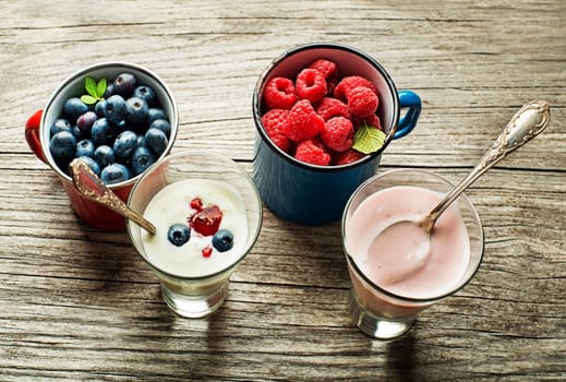 Bowl of fresh mixed berries and yogurt with fresh blueberries, raspberries served on a wooden table