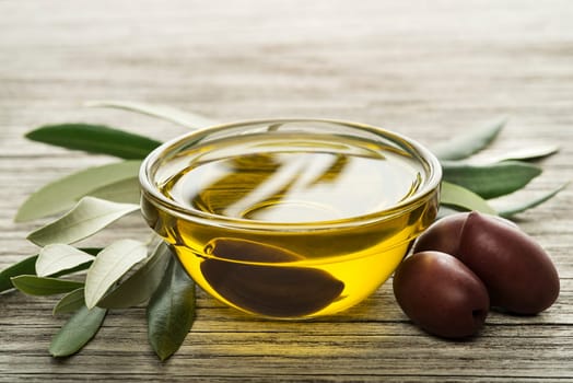 Olive oil with black olives on wooden background