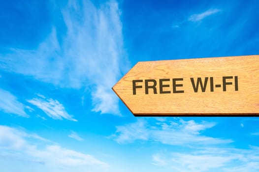 Wood arrow sign against clear blue sky with Free Wi-Fi message