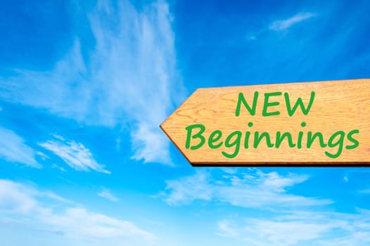 Wood arrow sign against clear blue sky with New Beginnings message, Life change conceptual image