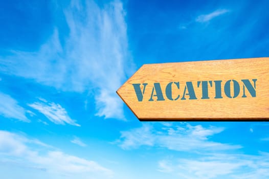 Wood arrow sign against clear blue sky with Vacation message,  Leisure concept