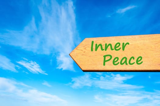Wood arrow sign against clear blue sky with Inner Peace message