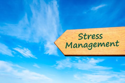 Wood arrow sign against clear blue sky with Stress Management message