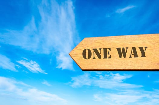 Wood arrow sign against clear blue sky with One Way message