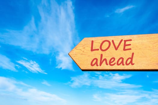 Wood arrow sign against clear blue sky with Love ahead message, Emotion and feelings concept
