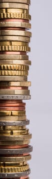 tower of coins in neutral grey background. Euro coins in a vertical stack.