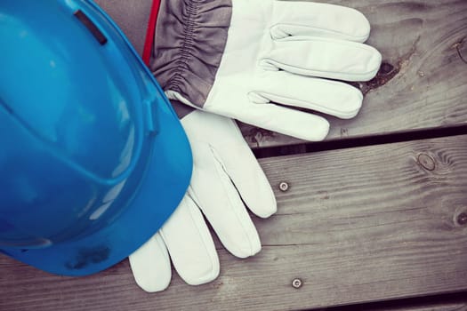 blue helmet and work gloves on wooden ground