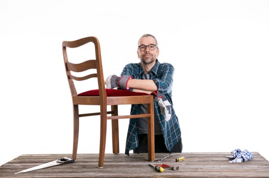 worker in blue plaid shirt repair old chair