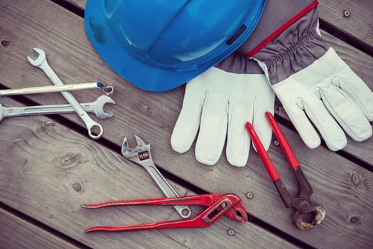 blue helmet different tools and work gloves on wooden ground