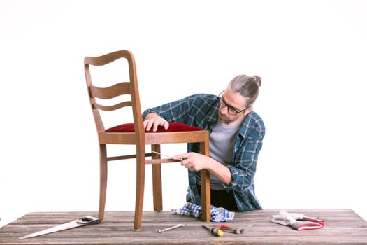 worker in blue plaid shirt repair old chair