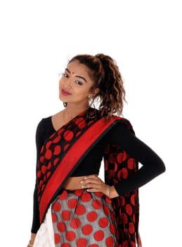 A beautiful East Indian teenager standing in a colorful Indian sari with .one hand on her hip and long curly hair, isolated for white background.