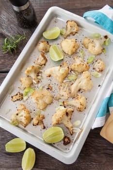 Baking sheet with roasted cauliflower and fresh lime